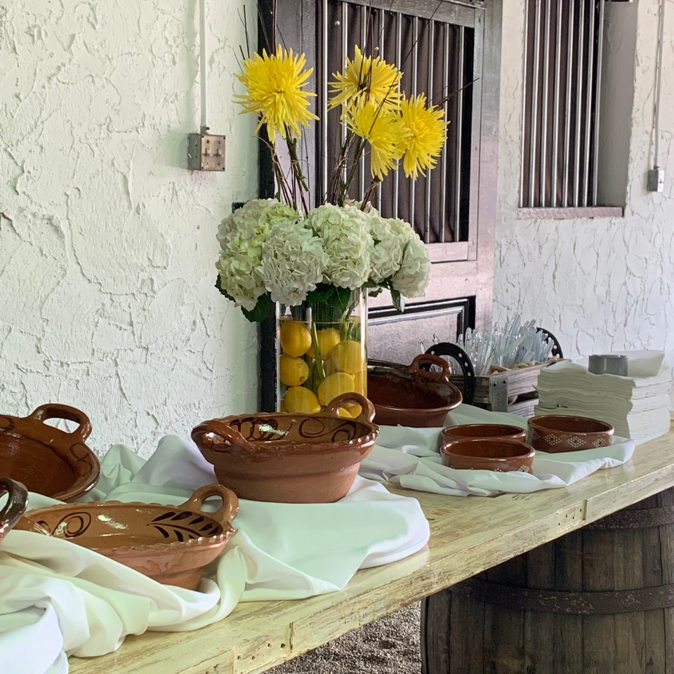 A buffet table with Mexican pottery, white linens, and floral arrangements with lemons.