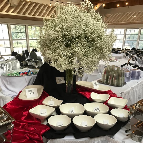 A Mexican buffet table with empty bowls for taco shells, corn chips, guacamole, and other toppings.
